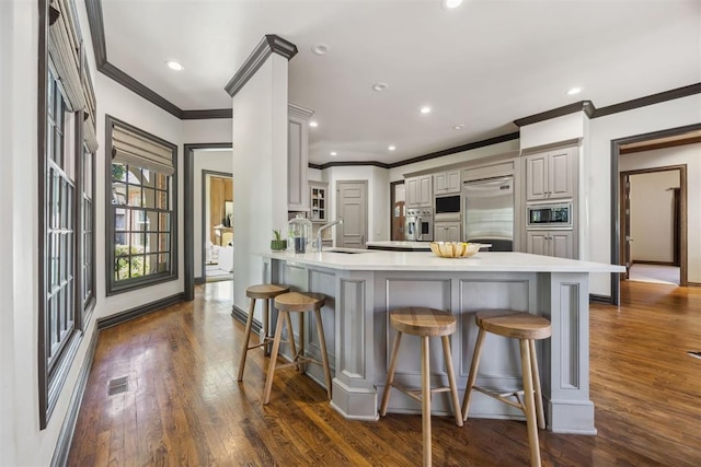 kitchen featuring built in appliances, sink, a breakfast bar area, and kitchen peninsula