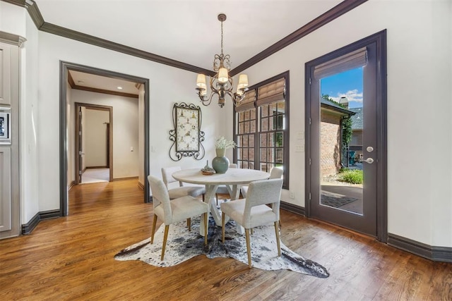 dining room featuring hardwood / wood-style flooring, crown molding, and a notable chandelier