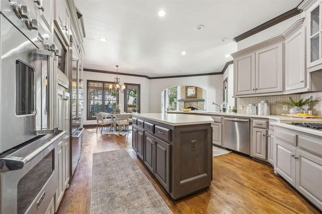 kitchen featuring decorative light fixtures, stainless steel dishwasher, decorative backsplash, and wood-type flooring