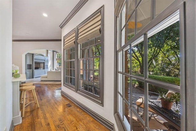 doorway to outside with wood-type flooring and ornamental molding