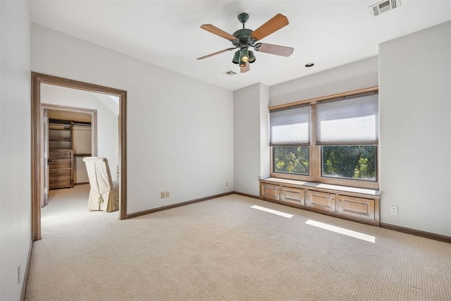 empty room featuring ceiling fan and light colored carpet