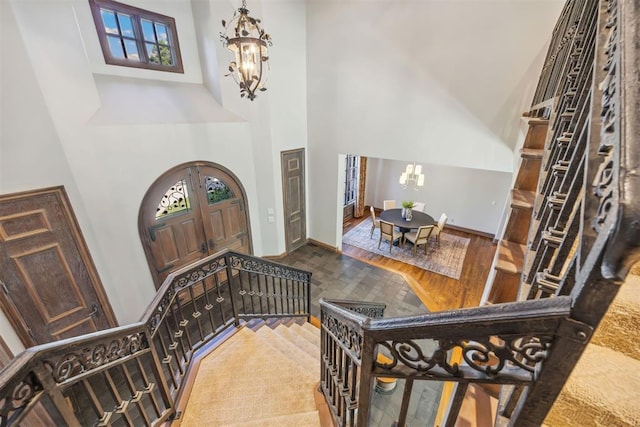 foyer entrance featuring hardwood / wood-style flooring, a healthy amount of sunlight, a chandelier, and a high ceiling