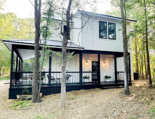 modern farmhouse style home with central air condition unit, covered porch, and metal roof