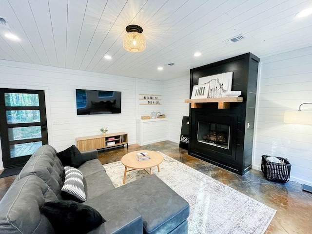 living area featuring finished concrete floors, recessed lighting, a large fireplace, and visible vents