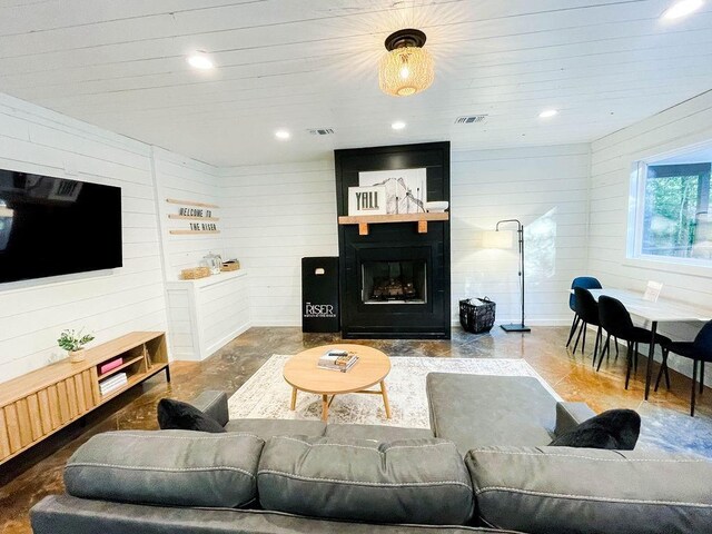living room featuring wood walls, a fireplace, visible vents, and recessed lighting