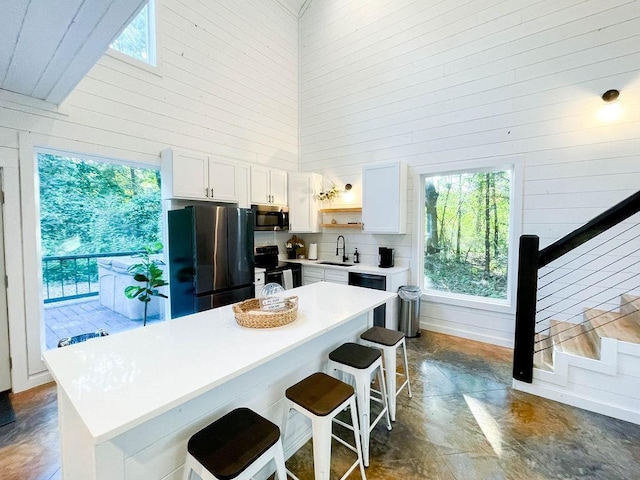 kitchen featuring electric range, stainless steel microwave, freestanding refrigerator, a high ceiling, and open shelves