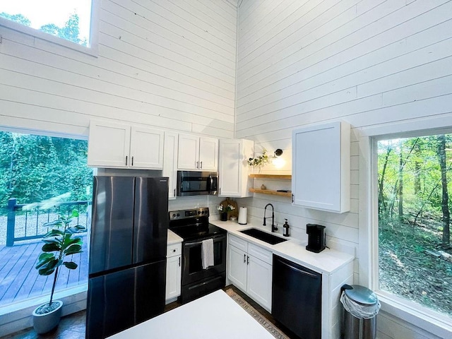 kitchen with stainless steel microwave, freestanding refrigerator, a sink, dishwasher, and black / electric stove