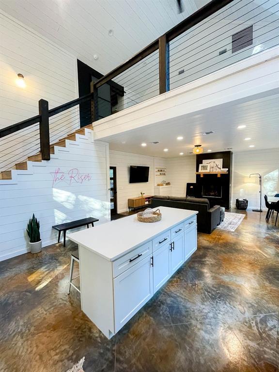 kitchen with a breakfast bar, a kitchen island, white cabinets, open floor plan, and light countertops