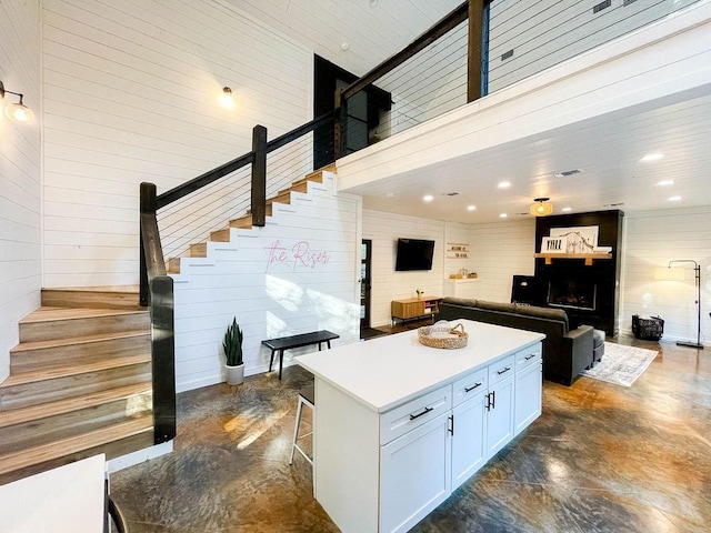 kitchen with concrete floors, a fireplace, white cabinetry, a center island, and a kitchen bar