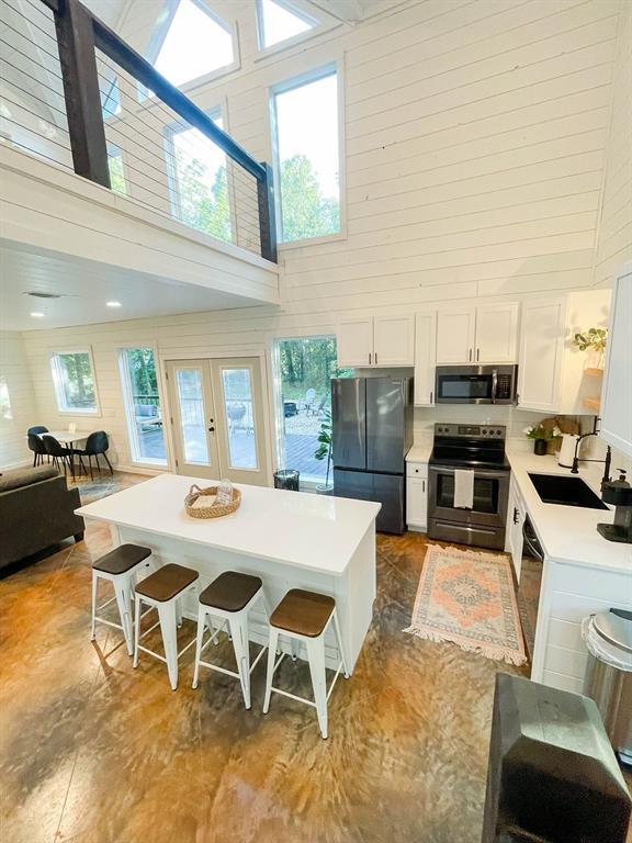 kitchen with stainless steel appliances, a breakfast bar area, a sink, and white cabinets
