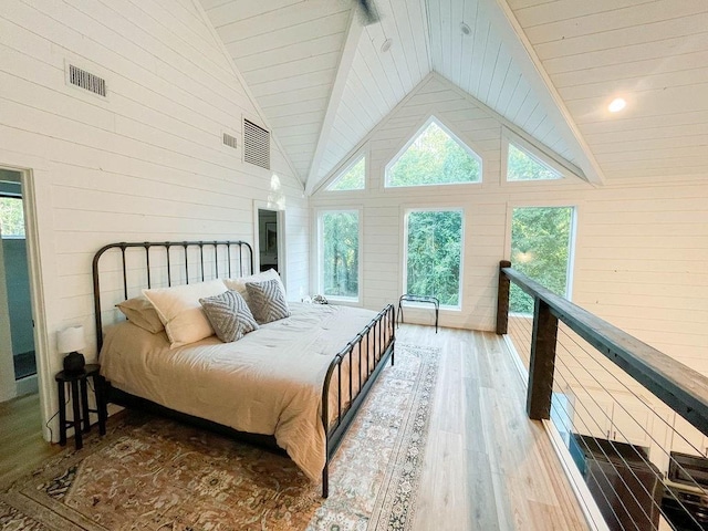 bedroom with high vaulted ceiling, visible vents, wood walls, and wood finished floors