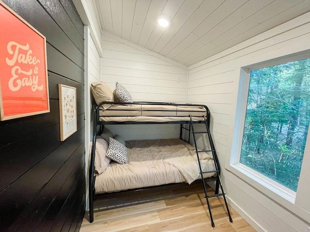 bedroom with wooden ceiling, vaulted ceiling, wood finished floors, and wood walls
