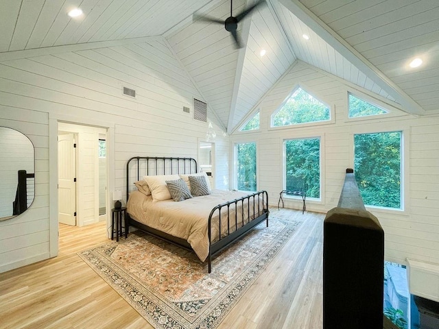 bedroom featuring light wood finished floors, multiple windows, visible vents, and wooden walls