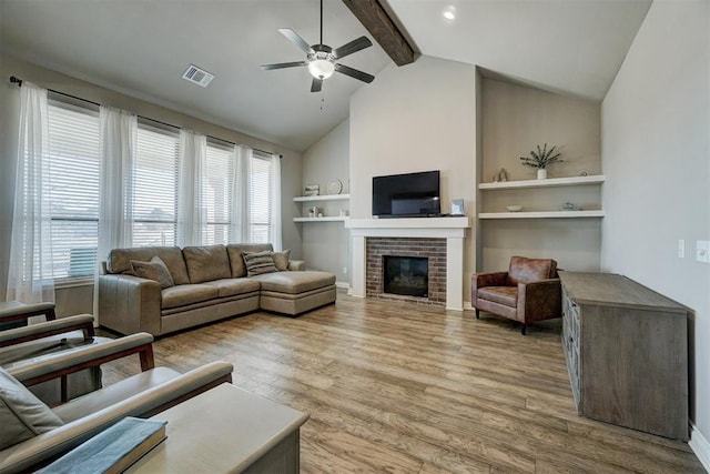 living room with a fireplace, beam ceiling, light hardwood / wood-style flooring, ceiling fan, and high vaulted ceiling