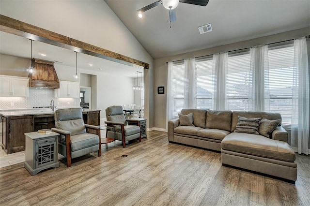 living room with light hardwood / wood-style floors, high vaulted ceiling, ceiling fan, and sink