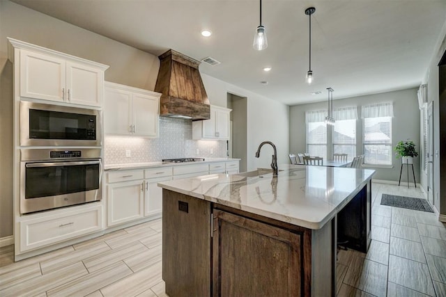 kitchen with white cabinetry, stainless steel oven, and premium range hood