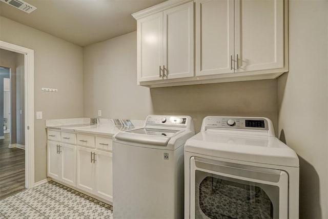 laundry room with independent washer and dryer and cabinets