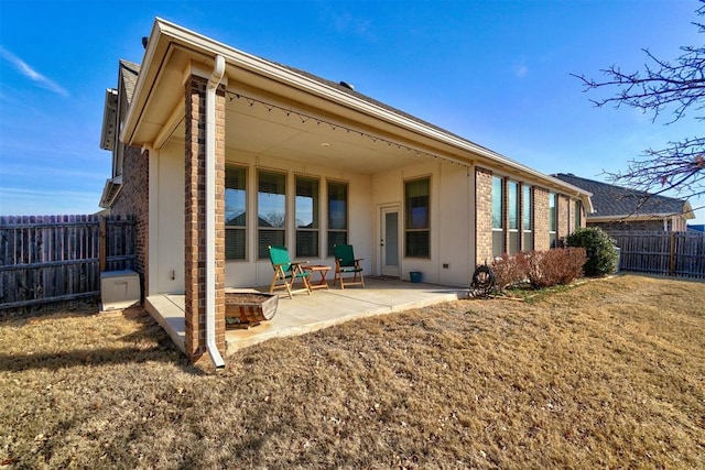 rear view of property featuring a patio, a fire pit, and a lawn