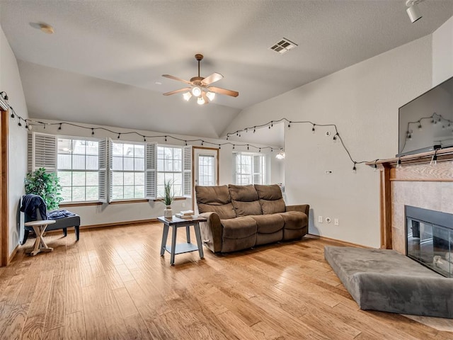 living room with vaulted ceiling, light wood finished floors, plenty of natural light, and visible vents