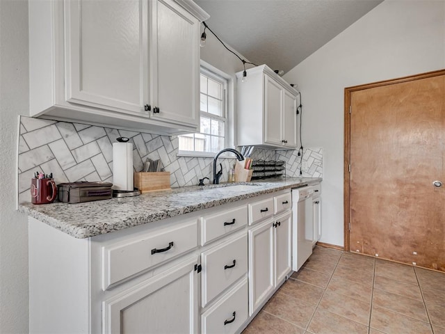 kitchen with lofted ceiling, white cabinets, light tile patterned flooring, a sink, and dishwasher