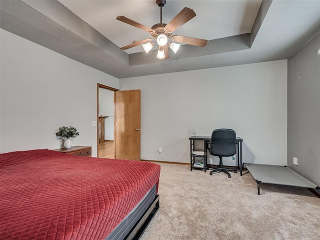 carpeted bedroom with a ceiling fan, a tray ceiling, and baseboards