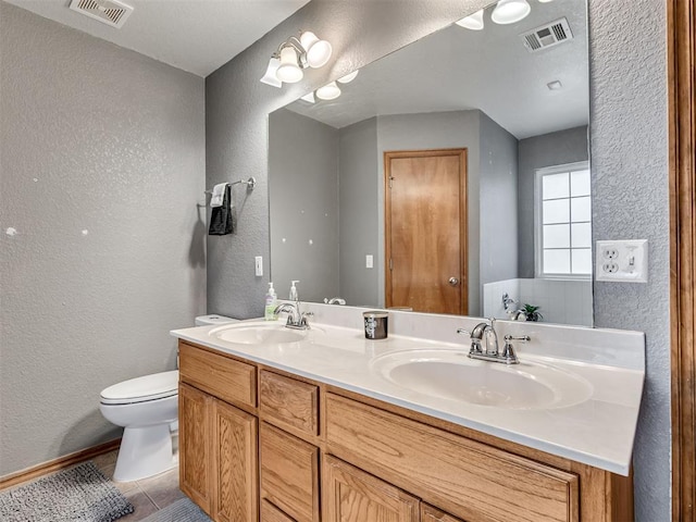 bathroom featuring toilet, visible vents, and a sink