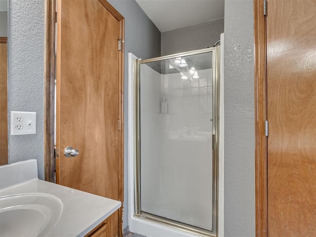 bathroom featuring a stall shower, vanity, and a textured wall