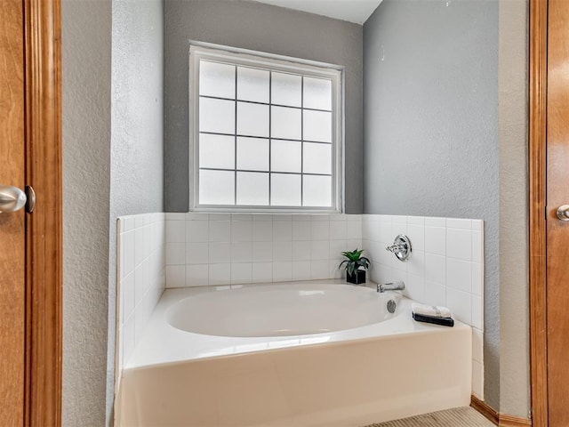 full bath featuring a garden tub and a textured wall