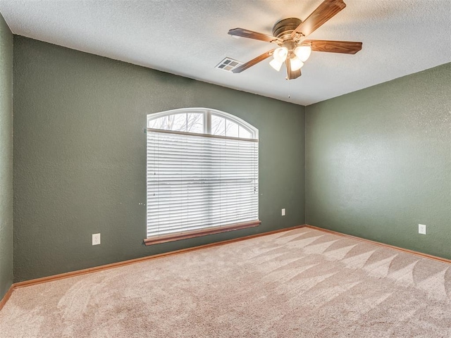 empty room with a textured ceiling, a textured wall, carpet, and visible vents