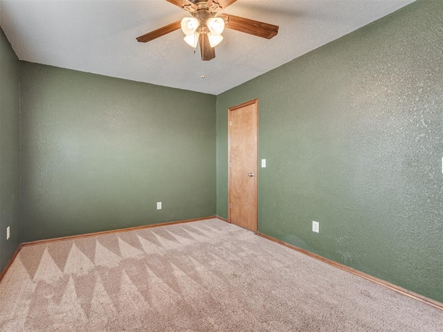 carpeted spare room with ceiling fan, baseboards, a textured ceiling, and a textured wall