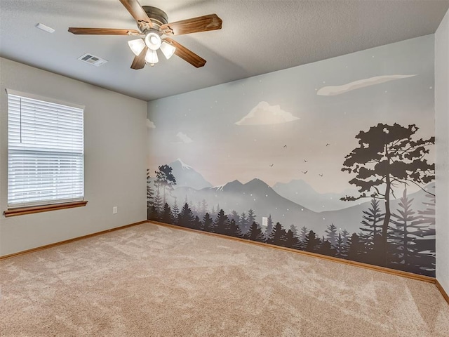 carpeted spare room featuring a ceiling fan, baseboards, visible vents, and a textured ceiling