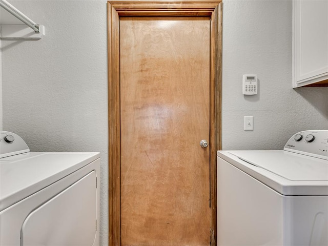 laundry area featuring cabinet space, a textured wall, and washing machine and clothes dryer