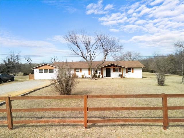 ranch-style home featuring a fenced front yard and gravel driveway