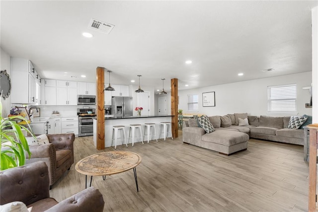 living area with light wood-type flooring, visible vents, and recessed lighting