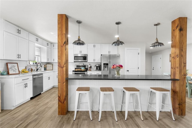 kitchen featuring white cabinetry, stainless steel appliances, decorative backsplash, and a kitchen breakfast bar