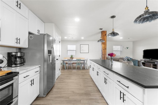 kitchen featuring white cabinets, light wood finished floors, open floor plan, and decorative backsplash