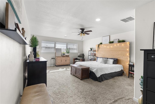 carpeted bedroom with a ceiling fan, visible vents, a textured ceiling, and baseboards