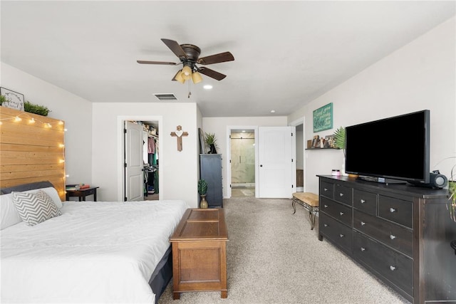 bedroom featuring a closet, visible vents, a spacious closet, light carpet, and ensuite bath