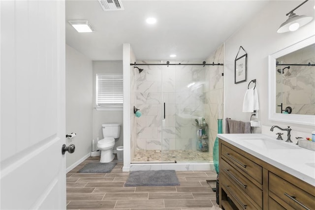 bathroom with a marble finish shower, visible vents, toilet, wood tiled floor, and vanity