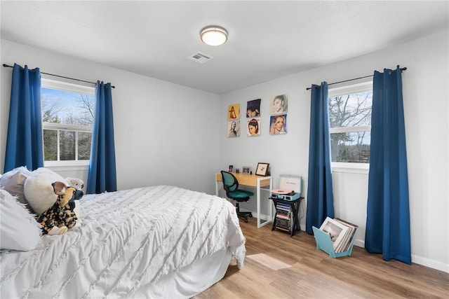 bedroom featuring light wood finished floors, visible vents, and baseboards