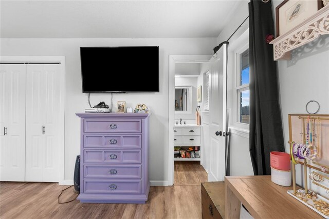 bedroom with light wood-style flooring, baseboards, and a closet