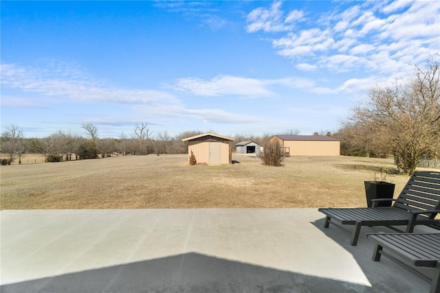 view of yard featuring an outbuilding, a storage unit, and a patio area