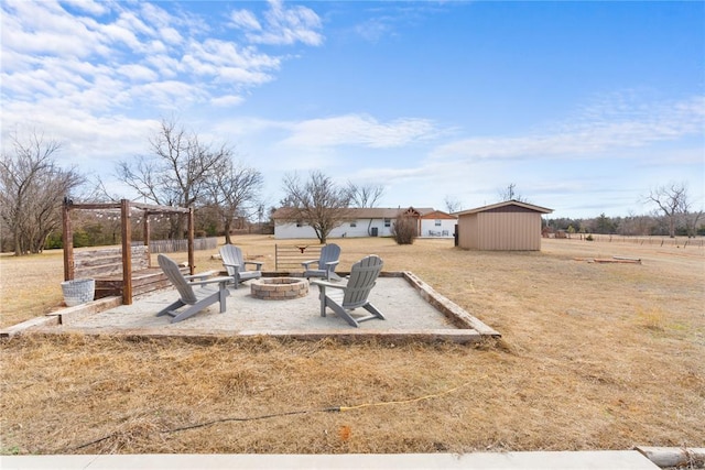 view of yard with a fire pit, a patio, a storage shed, and an outbuilding