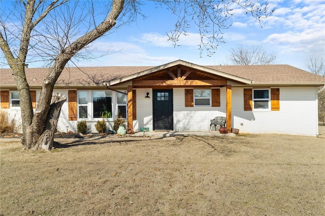 single story home with brick siding, a front yard, and a shingled roof