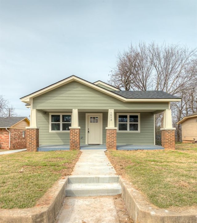 view of front of property with covered porch, brick siding, and a front yard