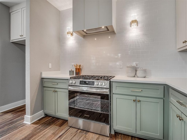 kitchen with light countertops, tasteful backsplash, light wood-type flooring, and stainless steel range with gas stovetop