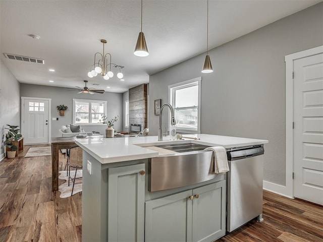 kitchen featuring a sink, open floor plan, light countertops, stainless steel dishwasher, and a center island with sink