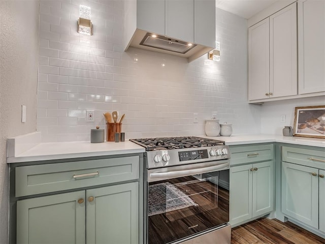 kitchen with dark wood-style floors, light countertops, decorative backsplash, gas range, and extractor fan