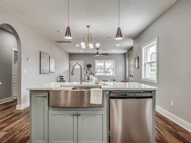 kitchen with arched walkways, visible vents, light countertops, stainless steel dishwasher, and an island with sink