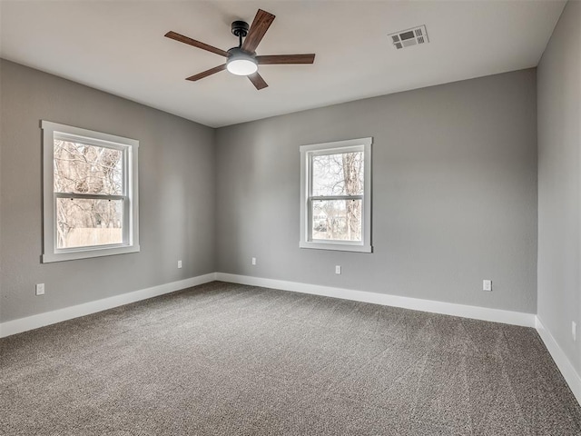 carpeted empty room with a ceiling fan, visible vents, and baseboards